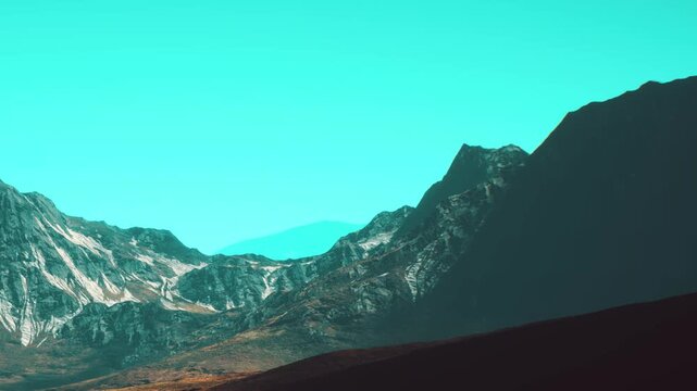 Mountains rise high with distinct shapes against a bright blue sky. The landscape shows rocky terrain and some green patches in the foreground.