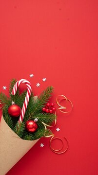 christmas holiday decoration with candy cane, fir branches, red baubles, and festive ribbons on red background