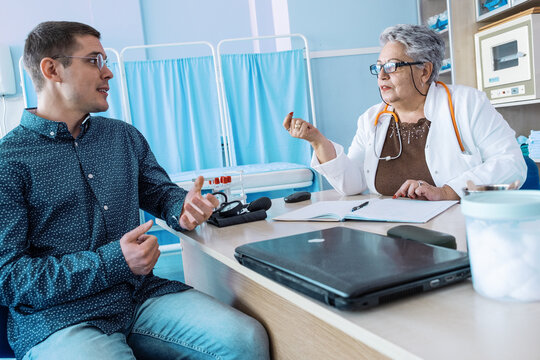 A patient is consulting with an experienced senior female doctor in her medical office, discussing their health and treatment options. The doctor listens carefully and explains the situation.