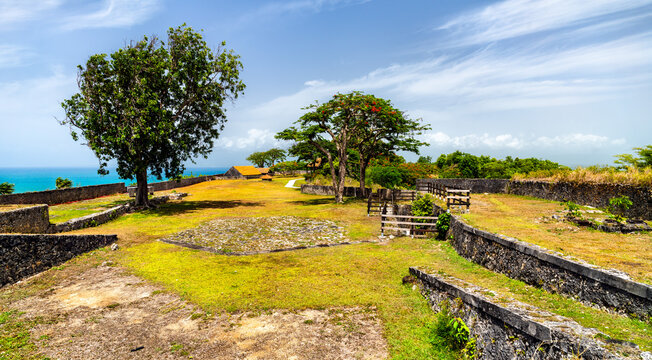 Scenic view of the historic stone walls and lush greenery at Fort Fleur d'Epee overlooking the Caribbean Sea in Le Gosier, Guadeloupe.