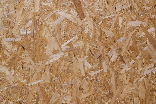 Close-up of OSB board with overlapping wood strands in brown tones.