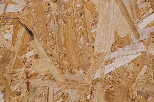 Close-up of OSB board with overlapping wood strands in brown tones.