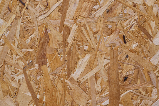 Close-up of OSB board with overlapping wood strands in brown tones.