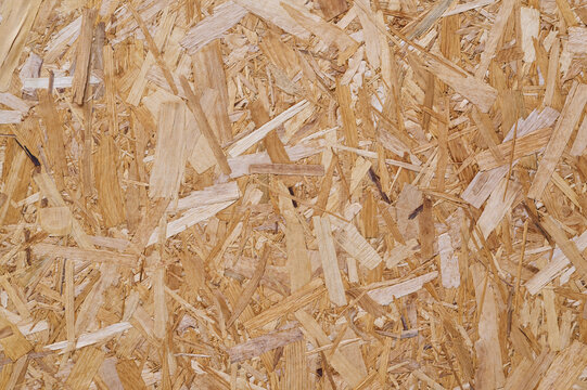 Close-up of OSB board with overlapping wood strands in brown tones.