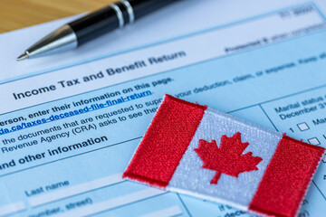 Obraz premium Tax return and application for benefits. Filing taxes in Canada. Canadian flag, tax form, and black pen. Close-up.