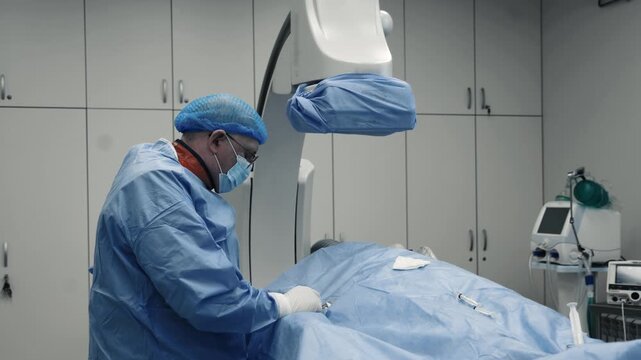 Doctor performing a medical manipulation in a sterile field during an interventional angiography procedure.