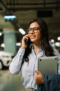Professional businesswoman talking on phone holding laptop