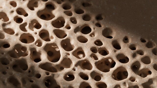 Extreme close up of 3D printed porous organic material with rounded cavities and fine layer lines under raking light - Material innovation and biomimetic design