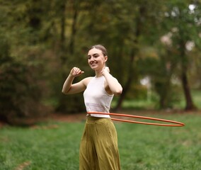 Athletic young woman exercising with hula hoop in park © New Africa