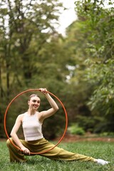 Athletic young woman posing with hula hoop in park, space for text © New Africa
