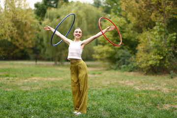 Athletic young woman exercising with hula hoops in park © New Africa