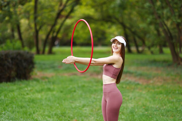 Athletic young woman exercising with hula hoop in park © New Africa