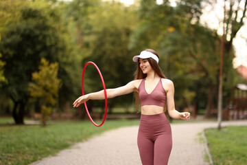 Athletic young woman exercising with hula hoop in park © New Africa