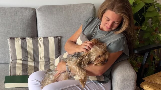 A middle-aged woman smiles happily as she caresses her adorable canine companion. She symbolises tranquillity and a tranquil state of mind.