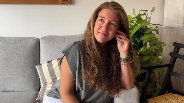 Portrait of a pensive and relaxed mature woman sitting on the couch in her living room