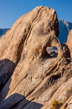 A rocky peak is visible through a small arch in the Alabama Hills of the eastern Sierra Nevada mountains in California