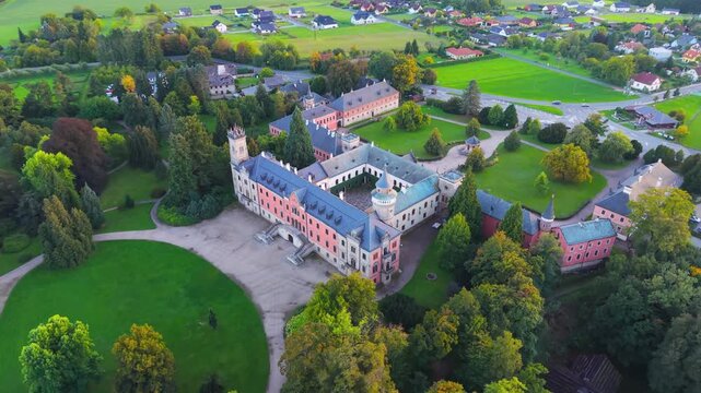 Aerial view of Sychrov Castle with its distinctive pink facade, courtyard, and surrounding lush green gardens in Sychrov, Liberec Region, Czechia.