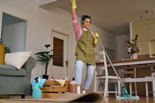 Woman enjoying housework dancing cleaning home
