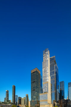 Reflective glass and stepped high-rise forms define the modern Hudson Yards real estate development in Manhattan, New York City, United States, with closely grouped towers viewed from street level.