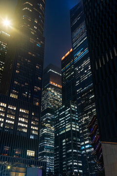 Low angle view showcasing a detail of the massive skyscrapers of the Hudson Yards real estate development in midtown Manhattan with brightly lit corporate office windows at night.