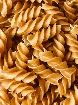 Full frame close up macro shot of uncooked whole wheat fusilli spiral pasta texture.