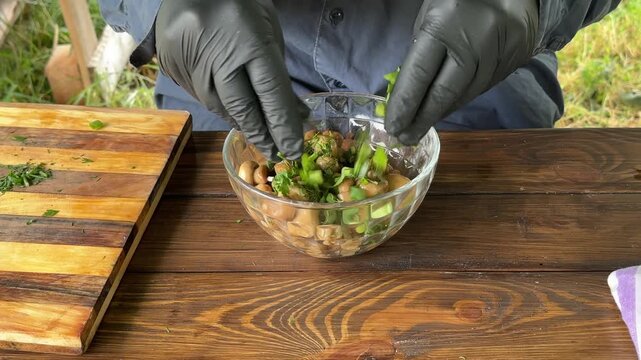 Pickled button mushrooms in a bowl are sprinkled with chopped herbs. High quality 4k footage