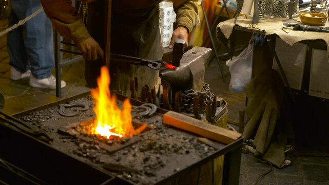 Blacksmith hammering a glowing hot metal on an anvil. Professional blacksmith forging a piece of red-hot metal with a hammer on an anvil next to a burning forge, embodying the craft of metalworking
