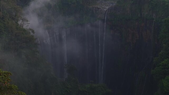Kecamatan Pronojiwo, Indonesia - 01 September 2026: Aerial view of Tumpak Sewu Waterfall with cascading water falling down the lush green cliffside in the misty tropical jungle.