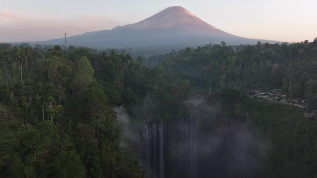 Kecamatan Pronojiwo, Indonesia - 01 September 2026: Aerial view of Tumpak Sewu Waterfall surrounded by lush tropical rainforest and the majestic Mount Semeru in the background.