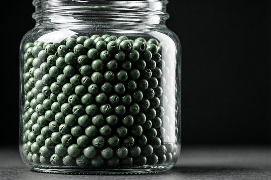 Green plastic airsoft BB pellets in a glass jar