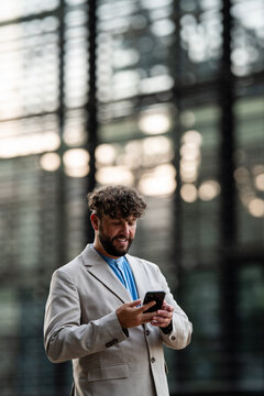 Smiling man using smartphone connecting urban outdoors