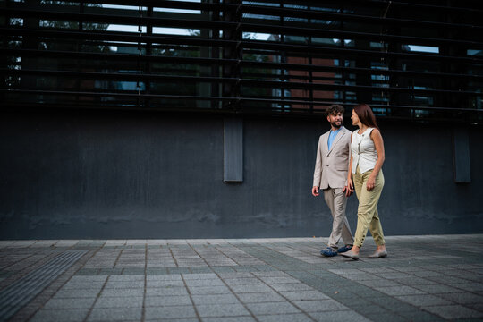 Business couple walking together discussing work in urban setting