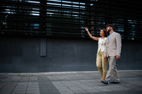 Business colleagues walking outdoors with woman hailing a taxi