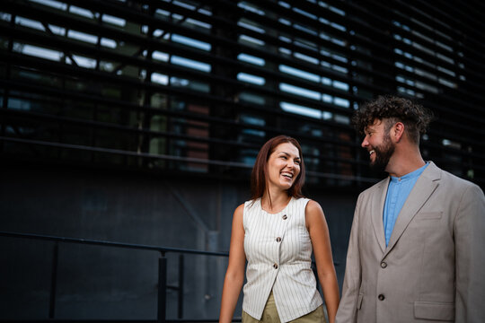 Smiling urban business couple walking in city street