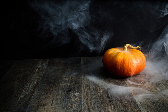 Pumpkin on wooden table creating spooky smoke effect