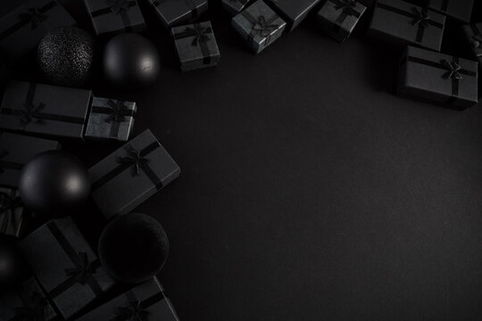 Black gift boxes and christmas balls on dark background