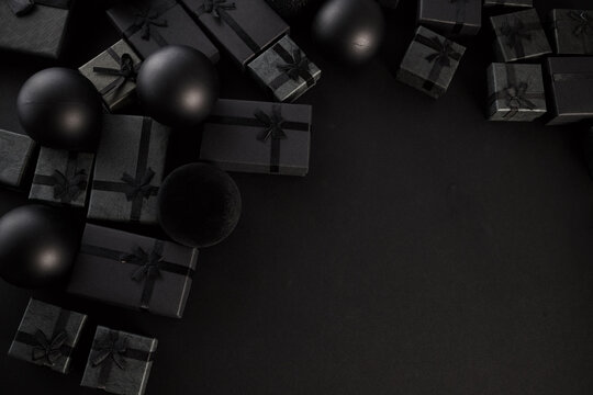 Black gift boxes with ribbon and ornaments on dark background