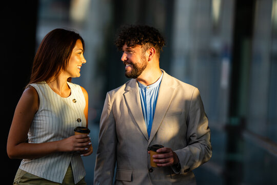 Business colleagues walking and talking during coffee break