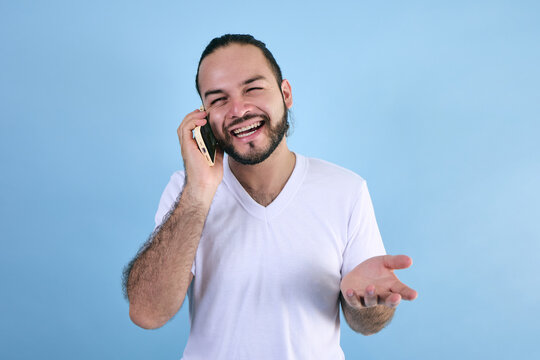 adult latin man talking by phone in a call on blue background in Latin America, latino male with face expressions in mexico