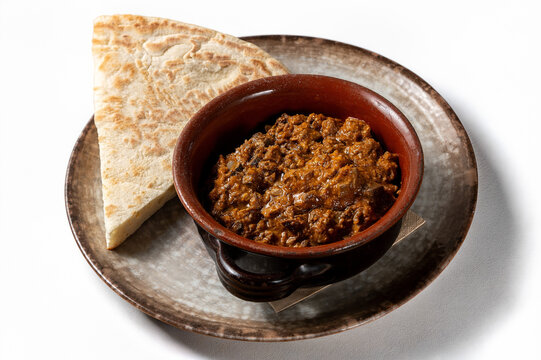 Traditional Umbrian lamb coratella served in a terracotta dish with torta al testo, isolated on a clean white background