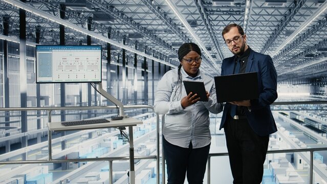 Woman and coworker optimize microchip workflow with EDA software in a smart factory while tracking semiconductor circuit layout defects with simulation tools.