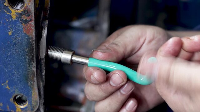 Static shot of a technician uses an installation tool to insert a helical thread repair insert during maintenance.