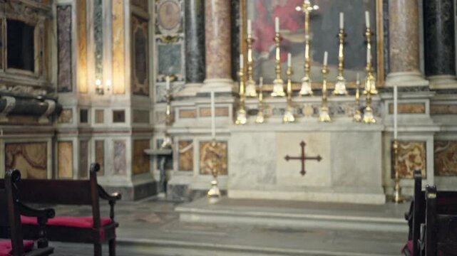 Blurred catholic church with soft bokeh altar, gilded candlesticks and out of focus wooden pews; background copyspace backplate template.