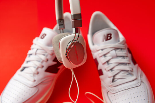 A Bowers & Wilkins P3 earcup hangs before New Balance sneakers on red.