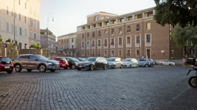 Defocused cobblestone street scene in rome with blurred cars, historic facades and soft bokeh background street; background backplate copyspace backdrop.