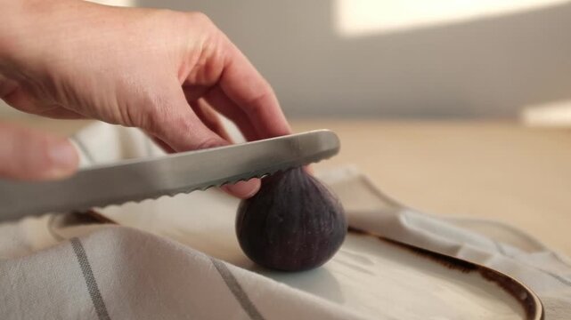 Fresh ripe figs sliced into quarters on a white ceramic plate with a kitchen towel, showcasing their vibrant pink pulp and dark purple skin. Perfect for healthy cooking blogs, organic food promotions.