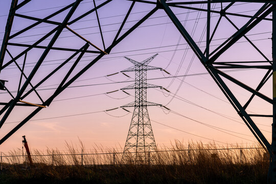 Transmission tower structure with electrical cables at dusk.