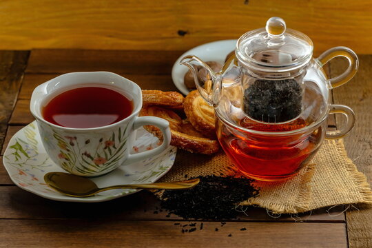 T&egrave; nero con teiera di vetro , tazza con piattino e pasticcini