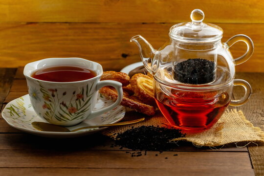 T&egrave; nero con teiera di vetro , tazza con piattino e pasticcini