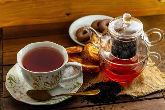T&egrave; nero con teiera di vetro , tazza con piattino e pasticcini